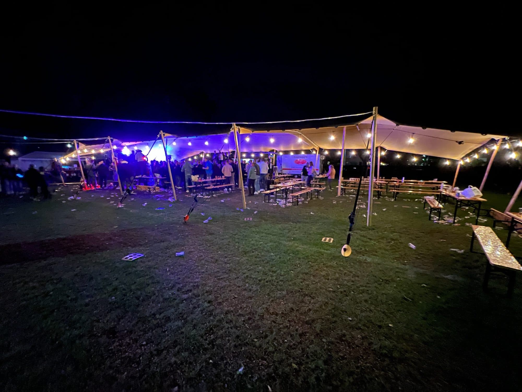 Stretchtent met kleurrijke verlichting op een festivalterrein in de avond