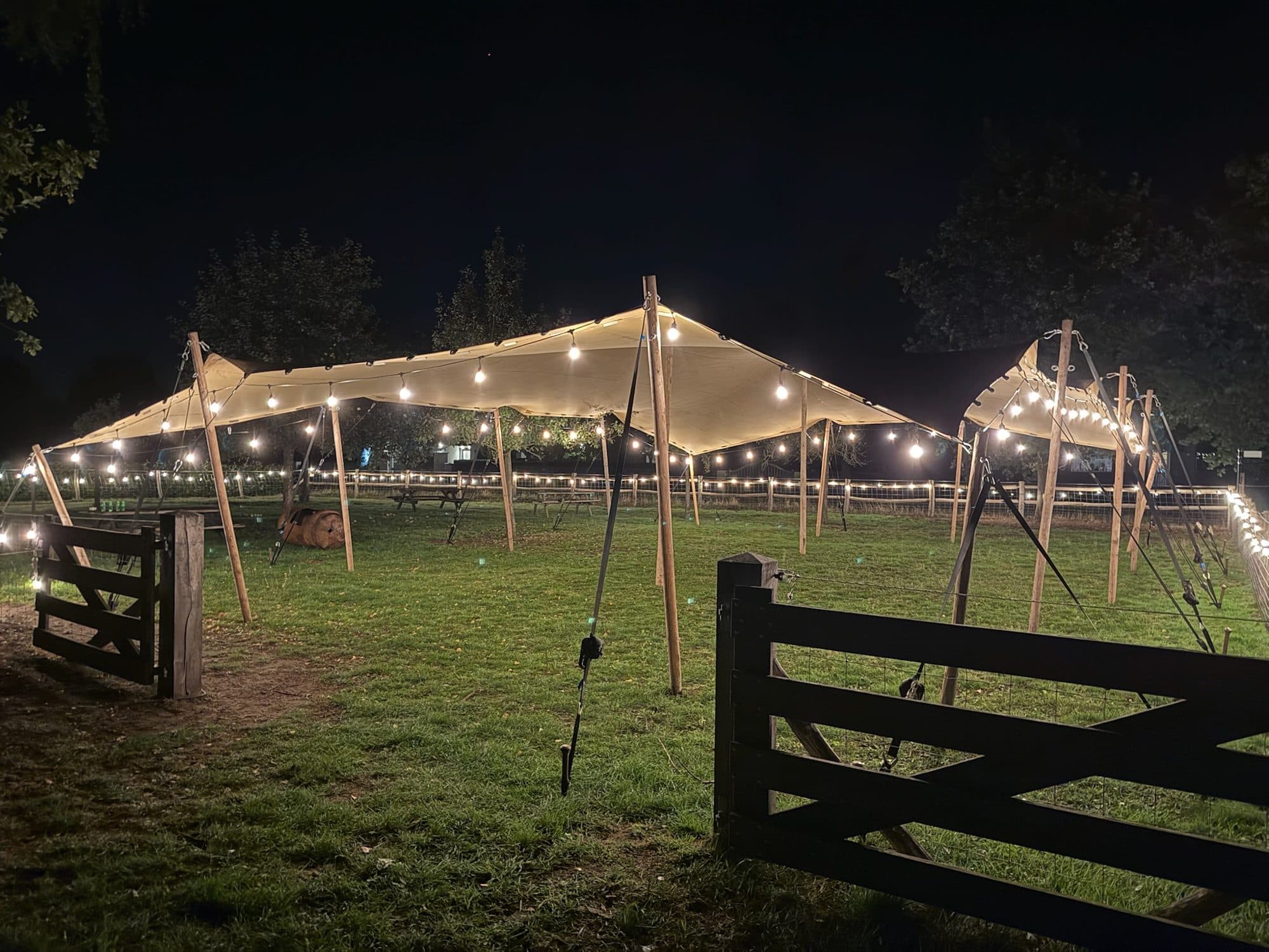 Stretchtent met prikverlichting op een grasveld in de avond