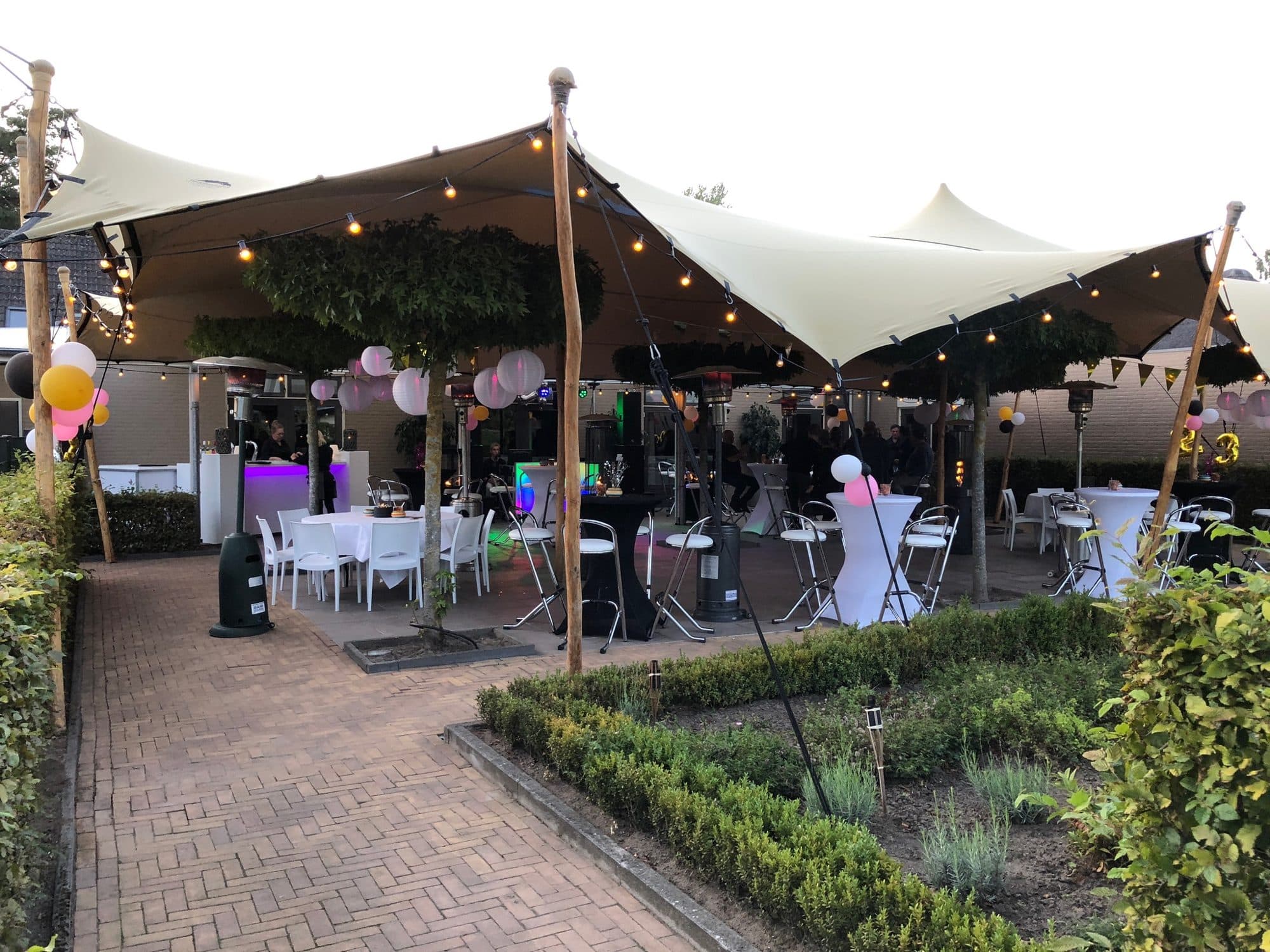 Stretchtent met gedekte tafels tijdens een tuinfeest
