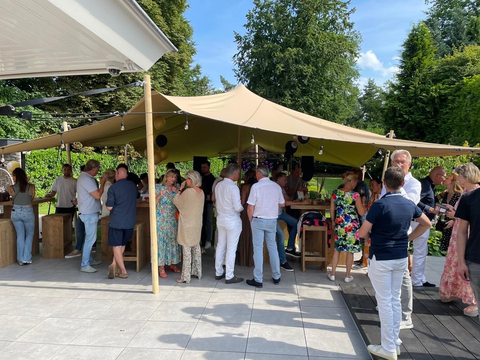 Gasten onder stretchtent tijdens een feest