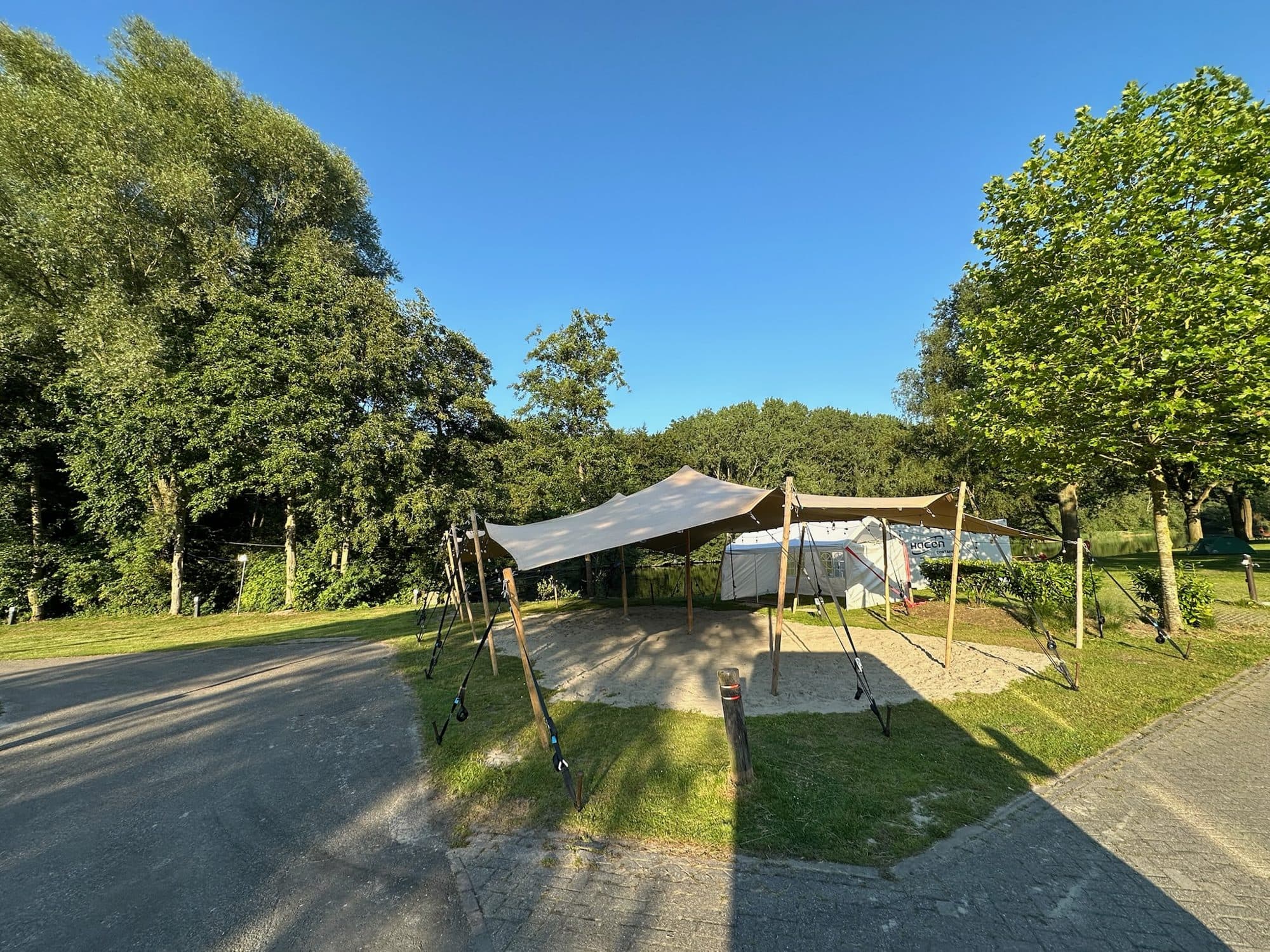 Stretchtent op een grindplek naast een grasstrook en een weg
