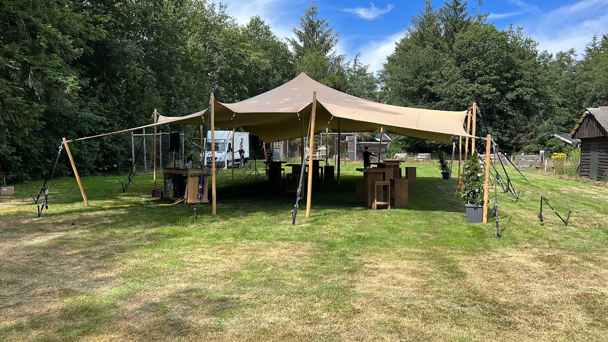 Stretchtent op een grasveld met houten tafels voor een verjaardagsfeest in de tuin